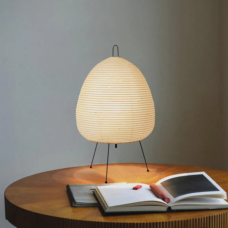 Japanese Rice Paper Lamp lit up resting on a glass table with a Bauhaus magazine